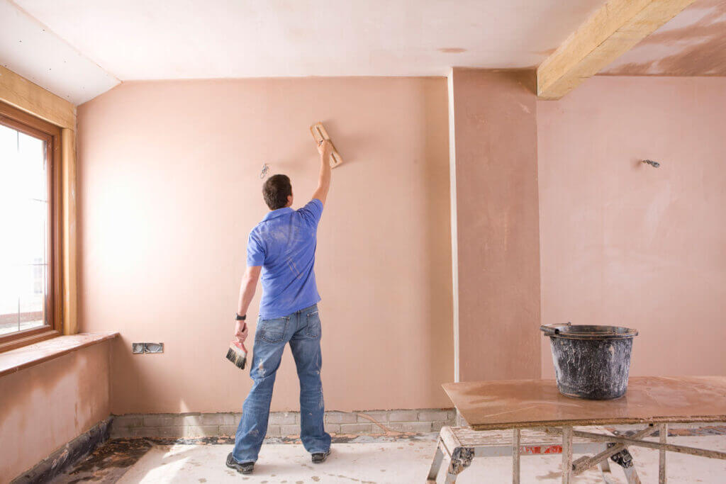 plasterer working on plastering full walls and ceiling